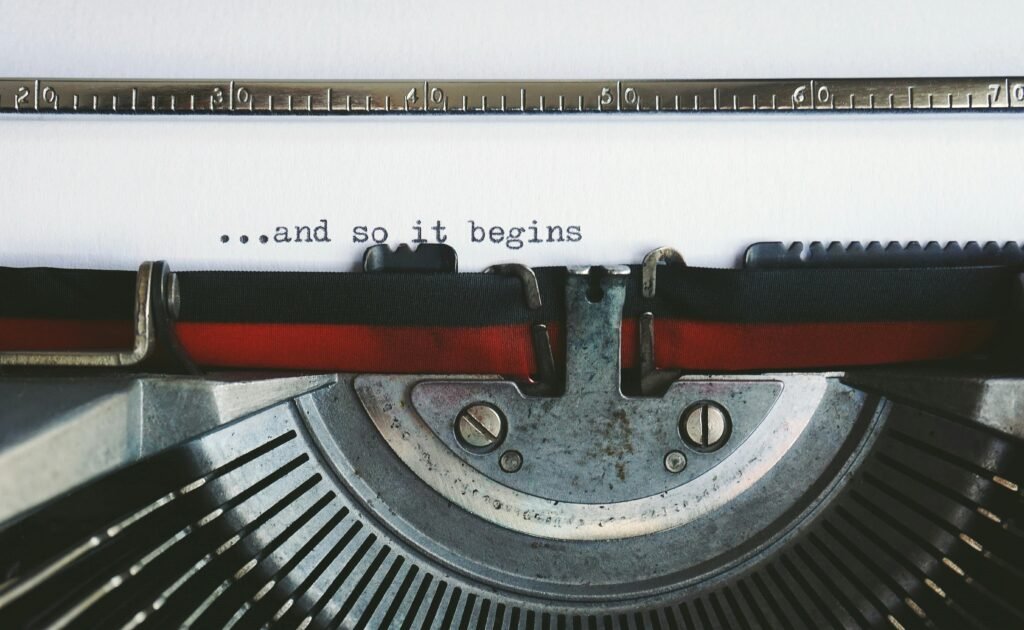 Close-up of a vintage typewriter with the quote '...and so it begins'.